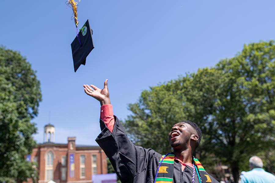 A 2021 Knox graduate tosses a mortarboard in the air