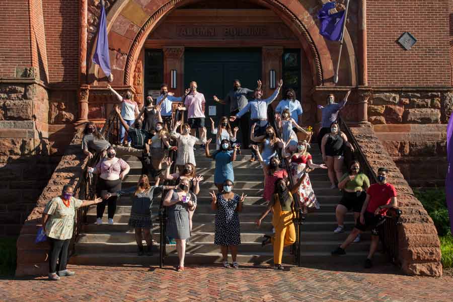 Students wear masks while posing for a photo outside the steps of Alumni Hall