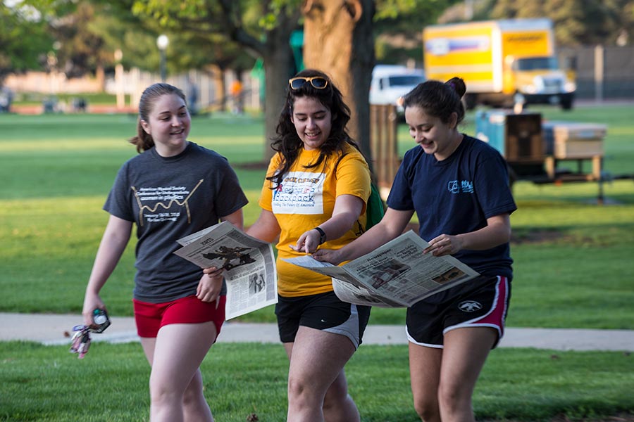 Three students discuss the current issue of The Knox Student as they walk across campus.