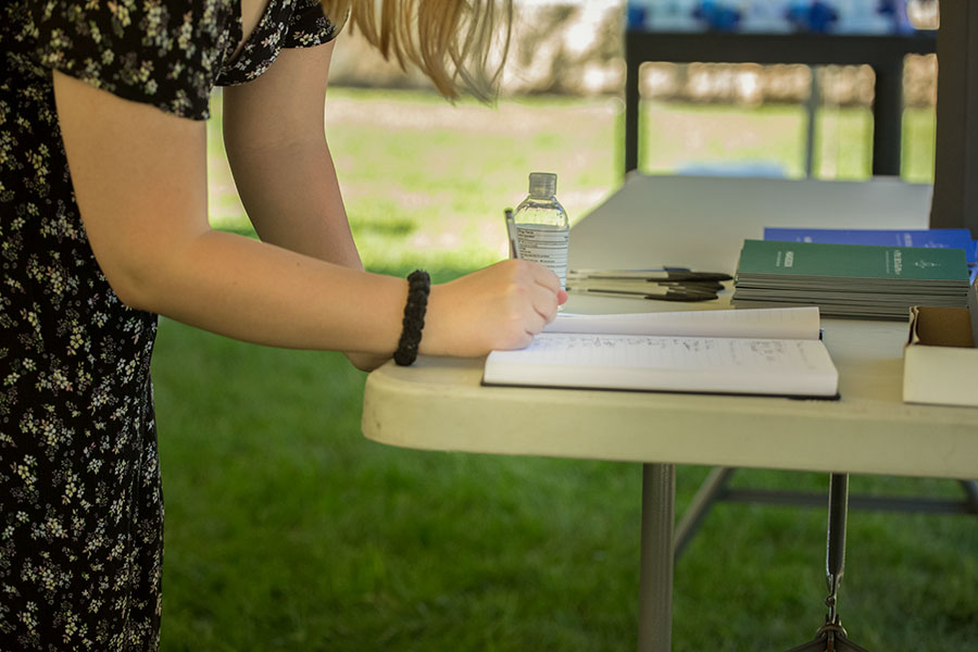 A student leans over a table to sign her name in the College's official Phi Beta Kappa book.