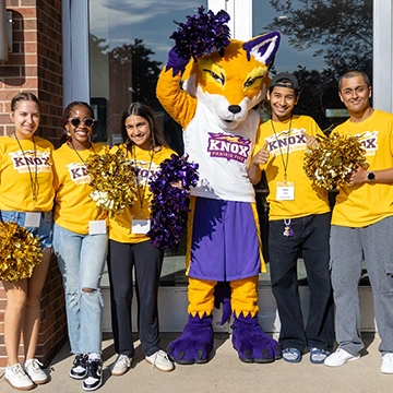 Five smiling Knox students pose for a photo with Blaze, the Prairie Fire Athletics mascot.