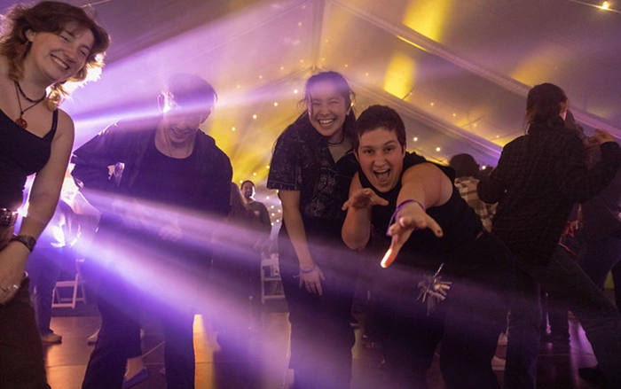 Venture Boldly attendees smile on the dance floor. One playfully makes clawing gestures at the camera.