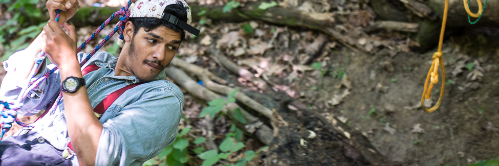 A student on a rope swing in the forest at Green Oaks.