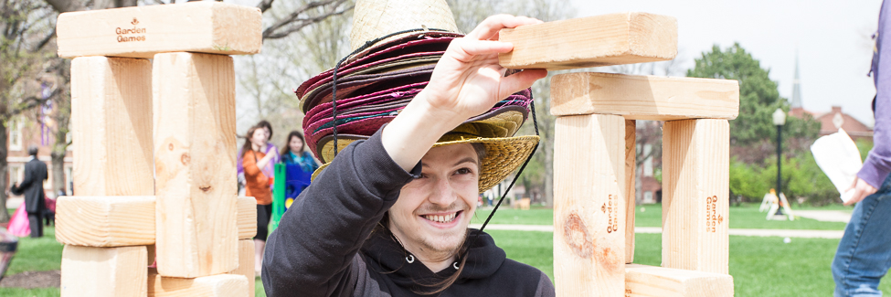 A student stacks blocks at a lawn game on Flunk Day.