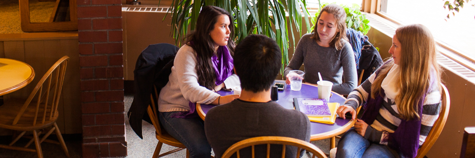 A group of students, talking at a table in the Gizmo.