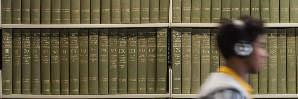 A student walks past a shelf of books in Seymour Library.