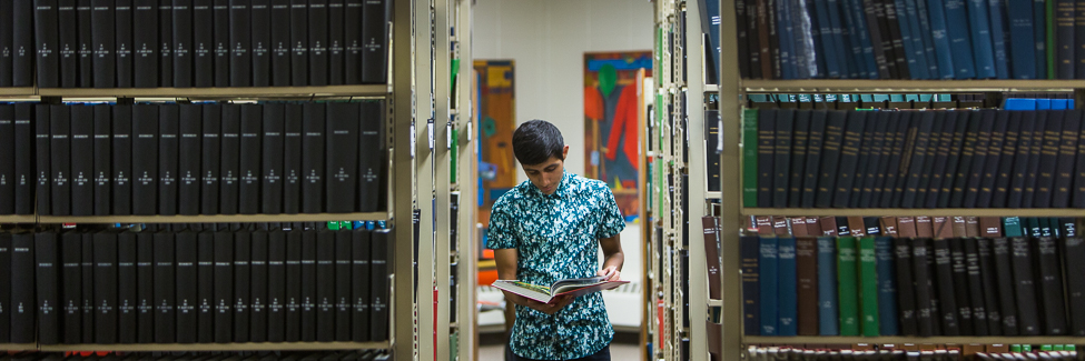 A student looks at a book in the shelves in Science Library.