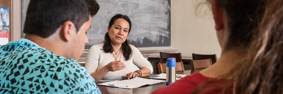 Professor Claudia Fernandez observes two students in a conversation-based exam.