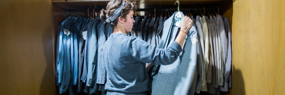 A student looks through theatre costumes.