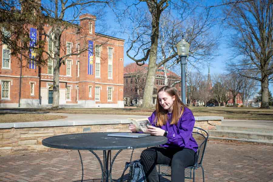 Emma Curry '22 sits on the Gizmo Patio and reads a book.