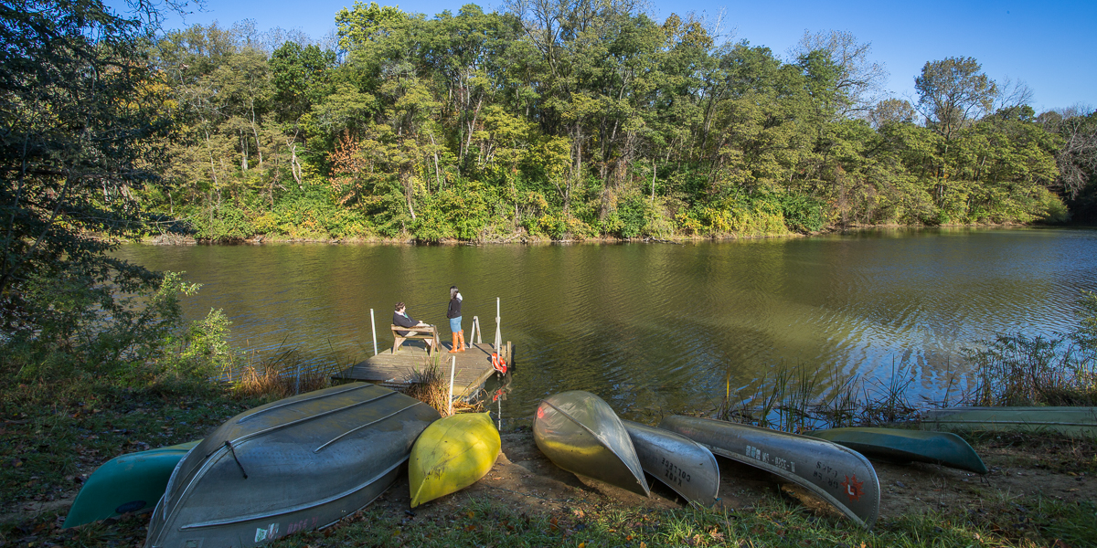 Canoes sit on the shore of a lake at the Green Oaks Biological Field Station.