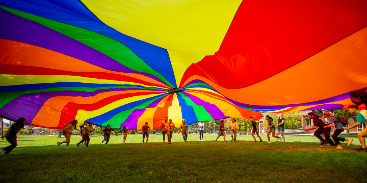 Students run under a parachute as part of an activity during International Orientation.