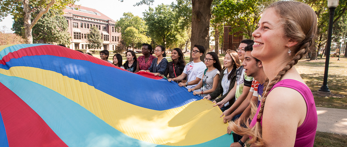 Students gather around a parachute as part of international student orientation.