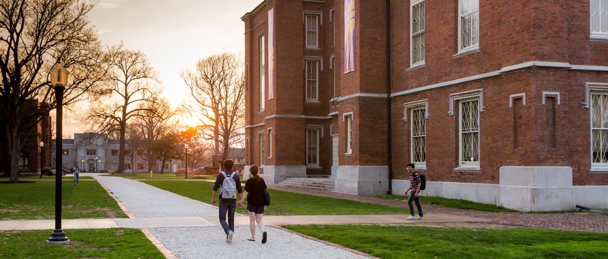 Students walk by Old Main in early evening. 
