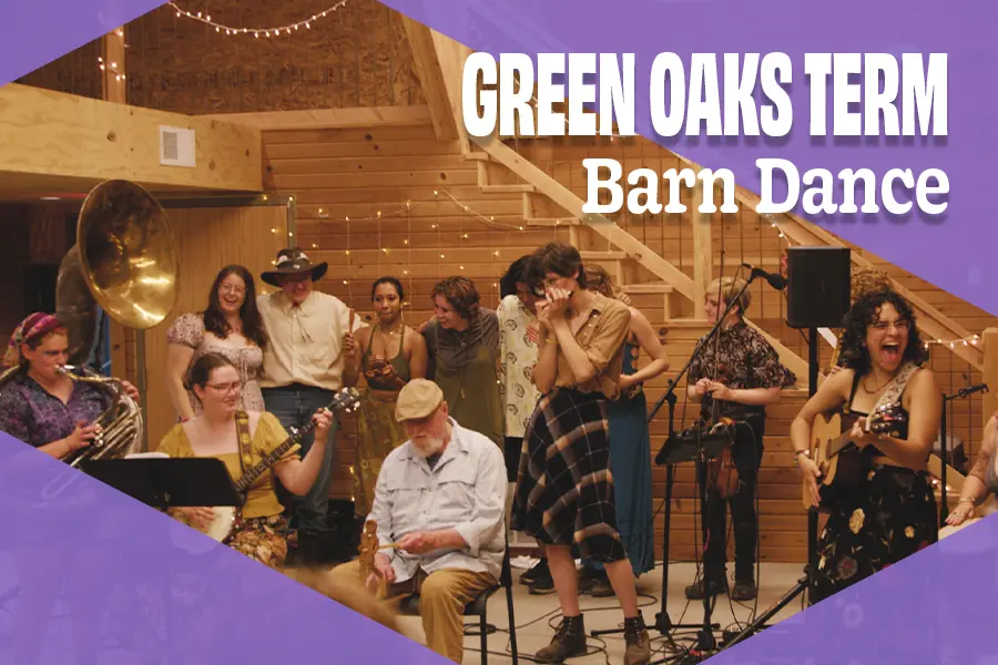 In a barn strung with white lights, a group plays musical instruments. Behind them, six individuals link arms.