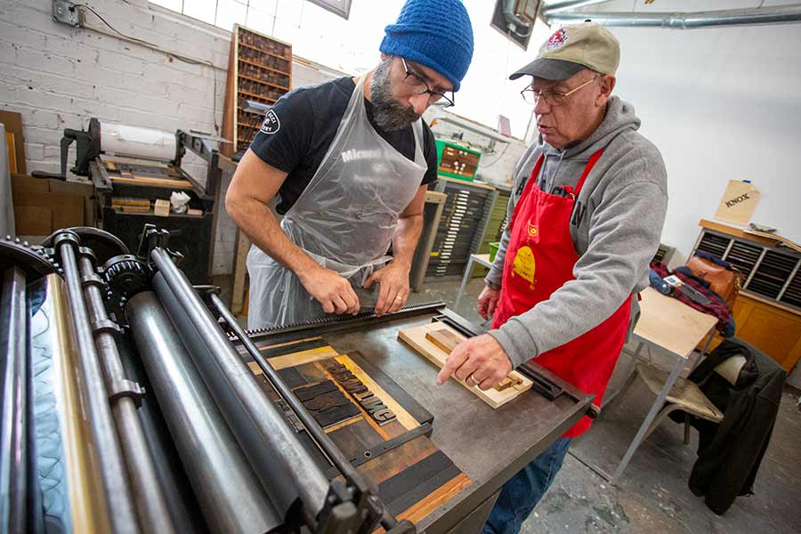 Faculty member Nick Regiacorte and donor Hal Keiner '67 install letterpress equipment.
